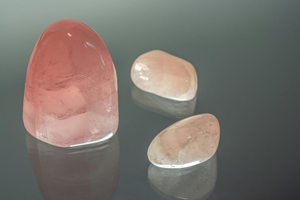 Close-up of polished rose quartz crystals on a glass surface, showcasing their natural beauty.